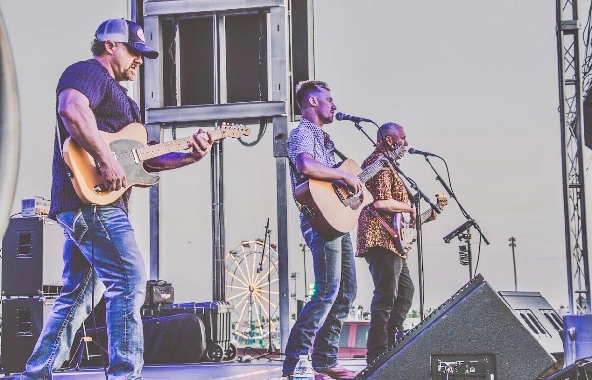 Dillon Leggett performing with his band at a county fair, ferris wheel in background