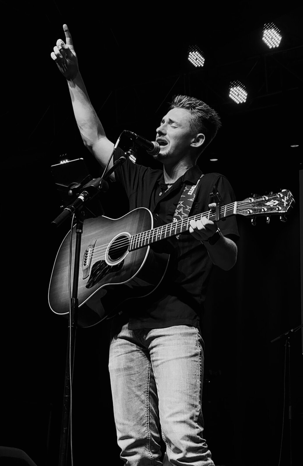 Dillon Leggett singing with arm raised, black and white