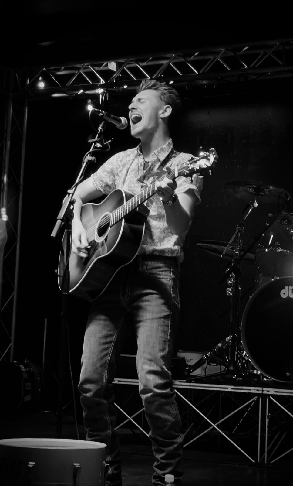 Dillon Leggett singing on stage, black and white