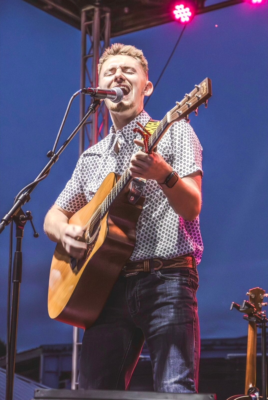 Dillon Leggett performing under blue and pink stage lights